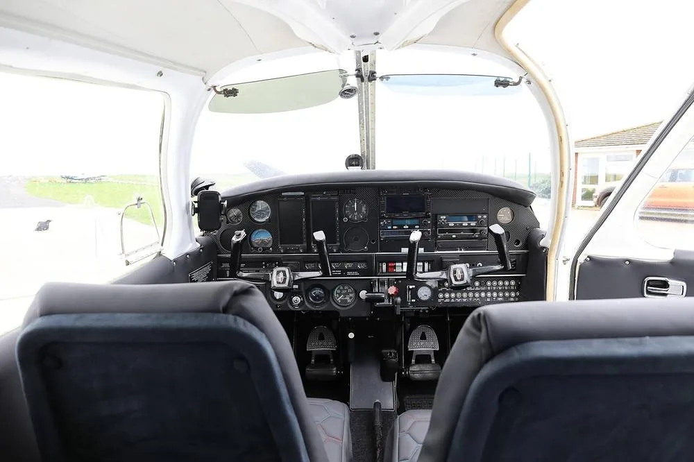 A view of the Piper PA-28 cockpit from the passenger seats, showing the instrument panel and controls.