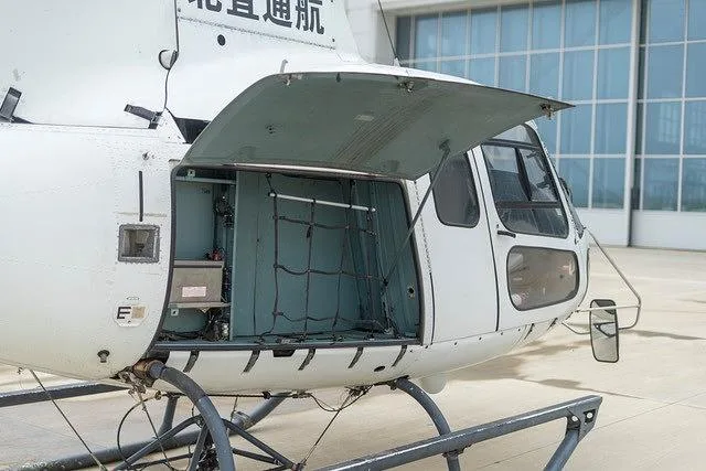 A close-up of the white helicopter's side, showing an open cargo compartment with a net.
