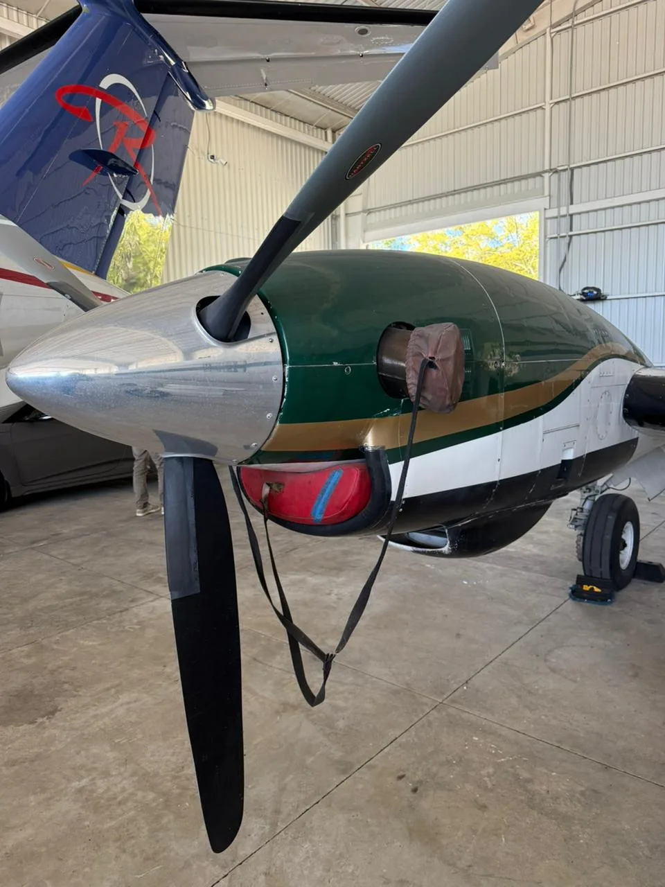Close-up of the right engine and propeller of a King Air C90 aircraft with a green and white paint scheme.