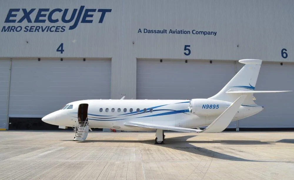 A Falcon 2000 LX parked in front of a hangar.