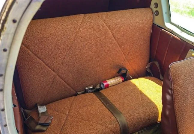 The rear cabin seats of an aircraft, upholstered in brown fabric with a geometric pattern.
