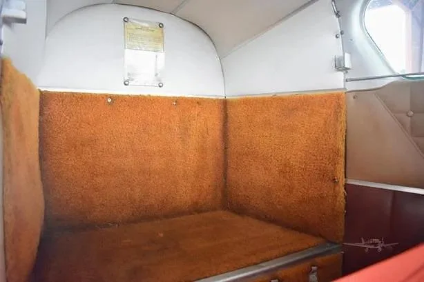 The rear interior of a general aviation aircraft cabin, featuring orange carpeted walls and floor.