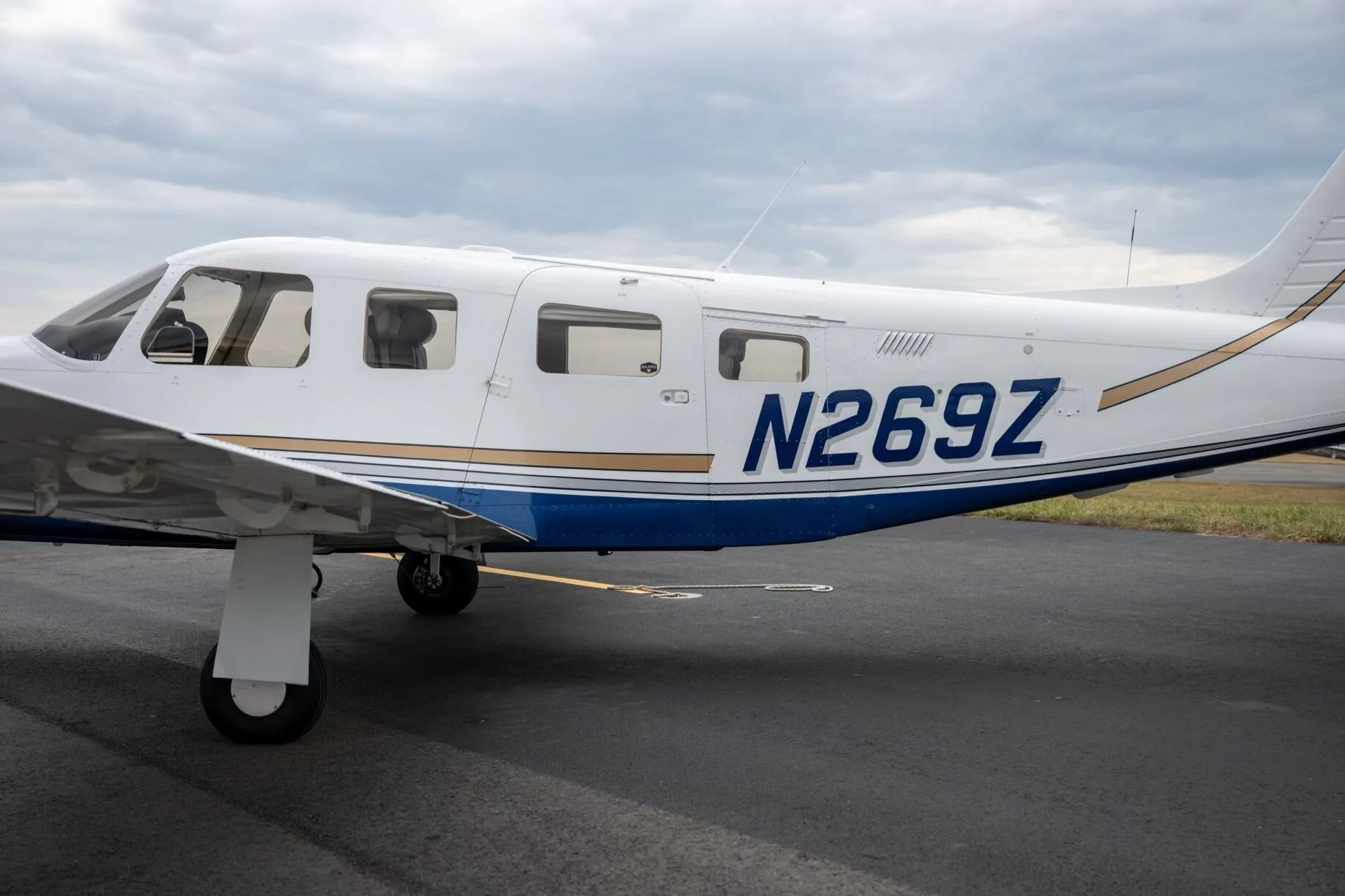 A close-up side view of the fuselage of a white Piper Saratoga II TC, showing the tail number N269Z and blue and gold stripes.
