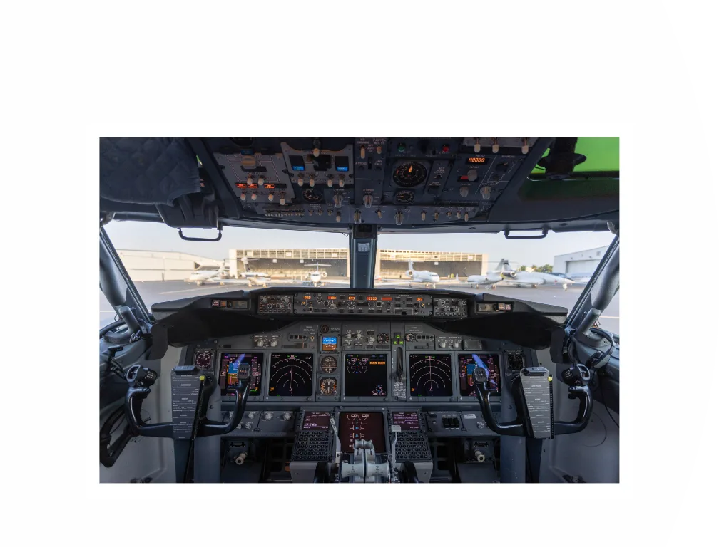 The modern cockpit of a Boeing 737, showing the instrument panel, yokes, and overhead panel.