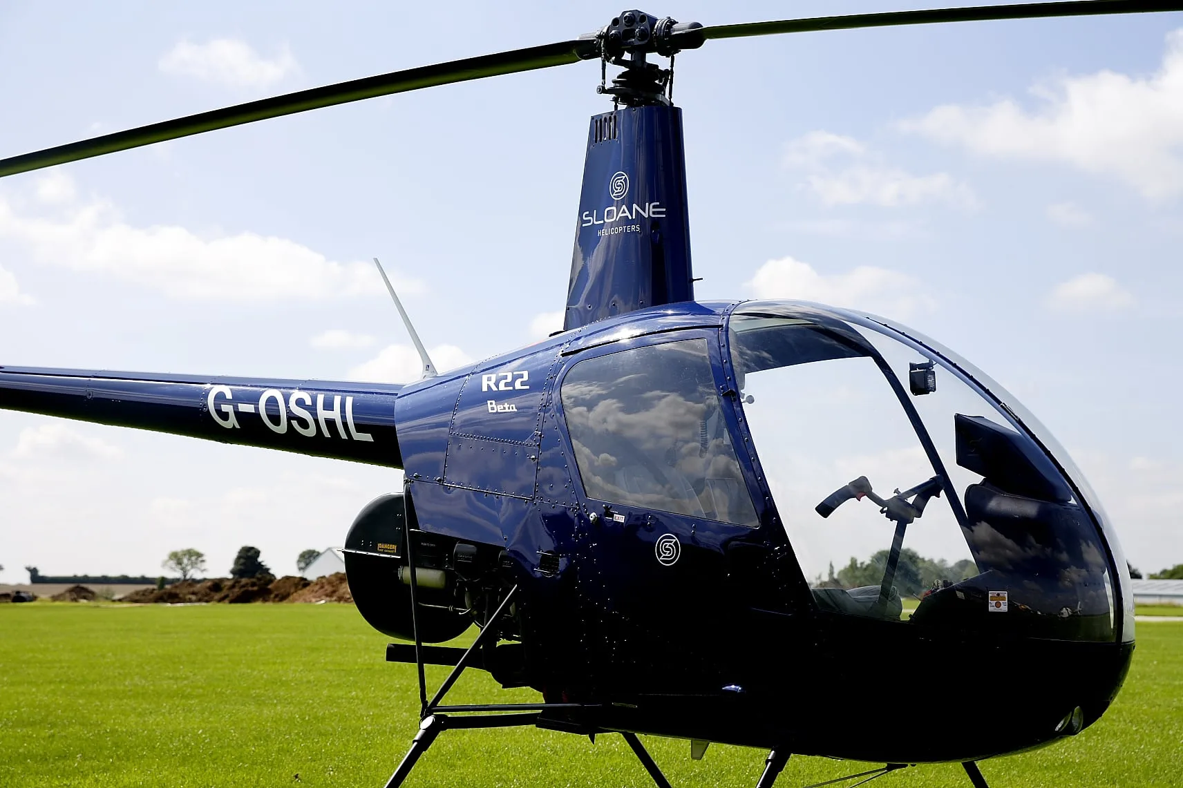 Close-up of a blue Robinson R22 helicopter on the ground.
