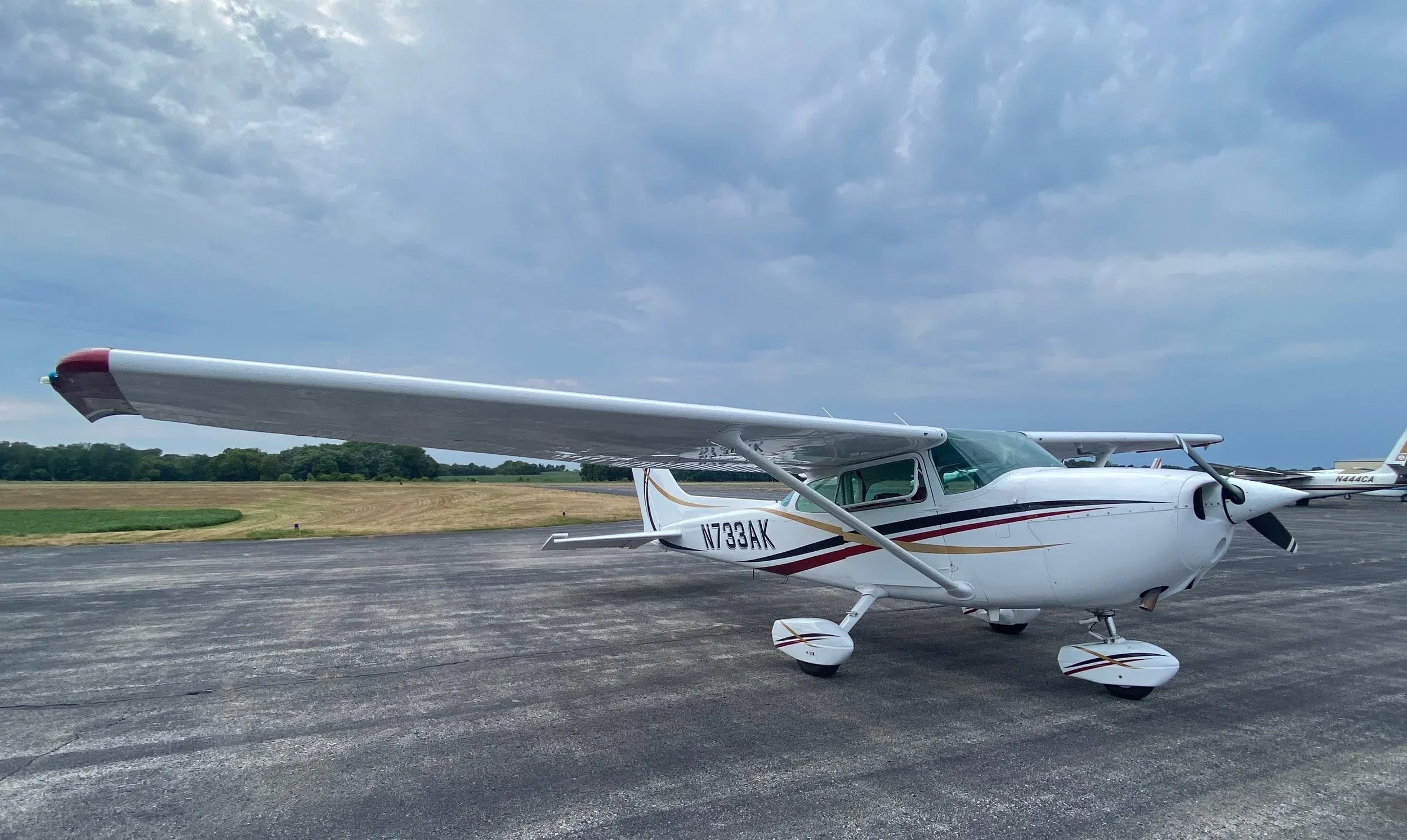 A Cessna 172 with a white and maroon paint scheme is parked on the tarmac.
