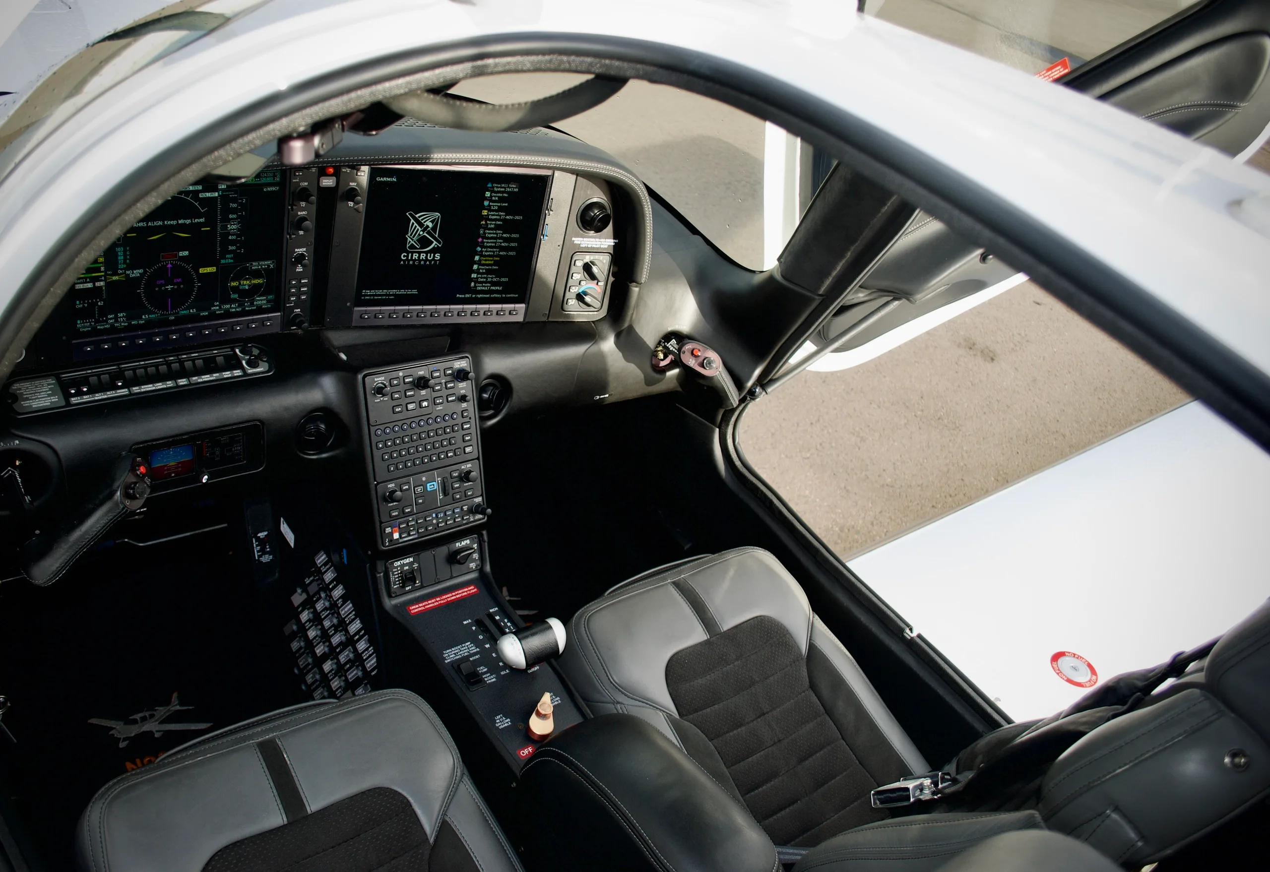 The cockpit of the Cirrus SR22T aircraft, featuring a modern glass panel display and gray seats.