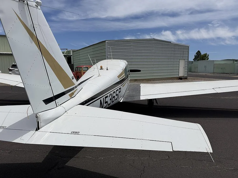 Rear-quarter view of the white and black Piper Comanche 250, registration N5365P, showing the tail and fuselage.