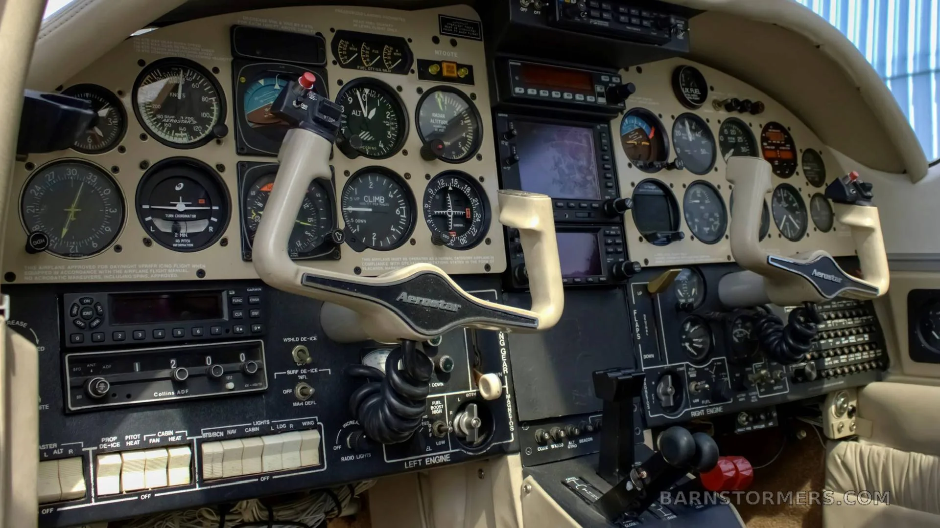 A wide view of the aircraft's cockpit, showing the instrument panel, dual yokes, and center console with various controls.
