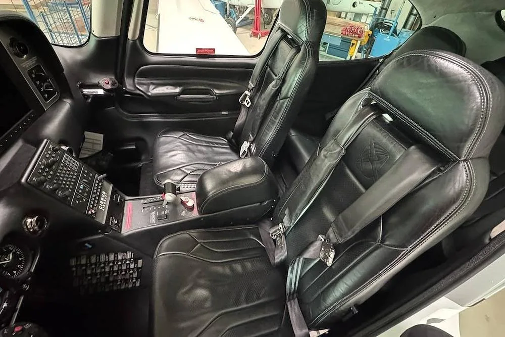 The black leather interior cabin of a Cirrus SR22 aircraft, showing the front and rear seats.