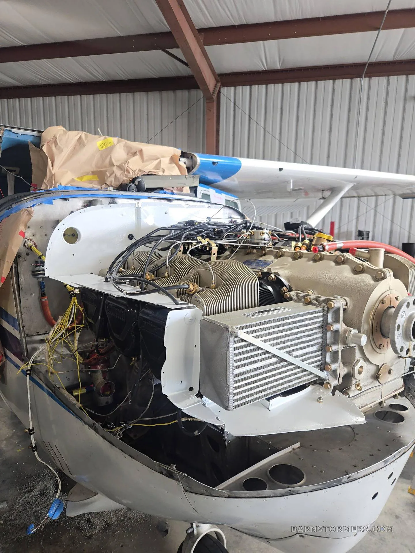 The exposed engine of a white and blue Cessna 182 aircraft, N8727Z, undergoing maintenance in a hangar.