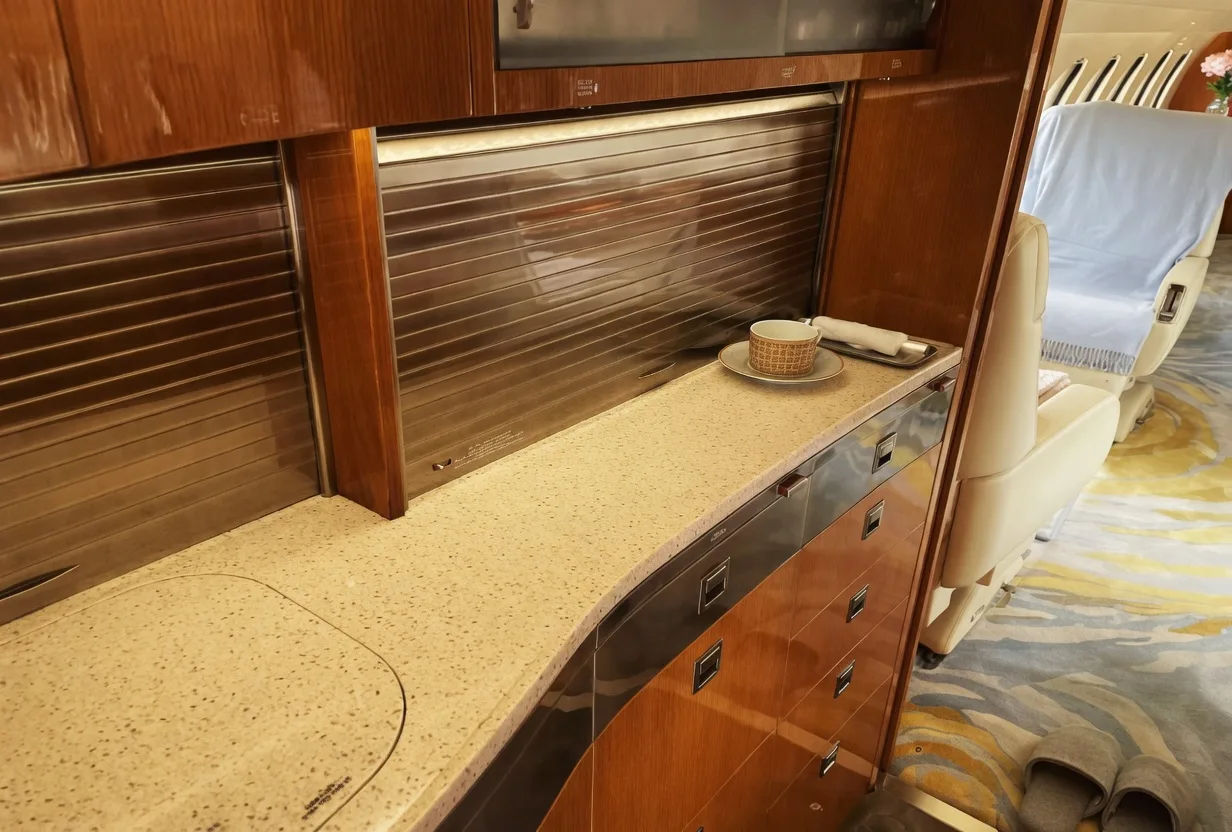 A close-up view of an aircraft galley with wooden cabinetry, a countertop, and a small cup on a saucer.