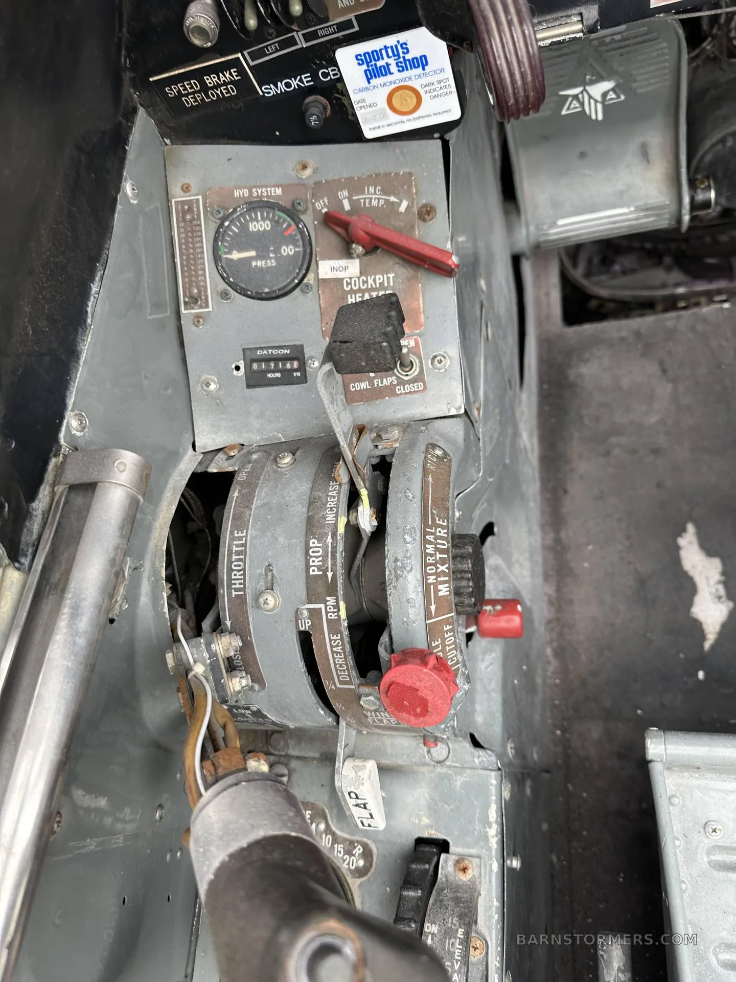 A close-up view of the throttle, propeller, and mixture controls, along with other switches, in a vintage aircraft cockpit.