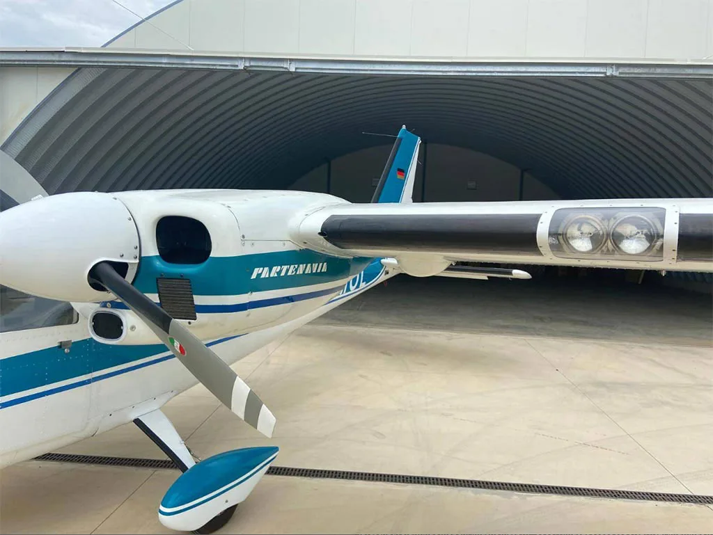 A close-up view of the front right side of a white and blue Partenavia P.68 aircraft, showing the propeller and engine nacelle.