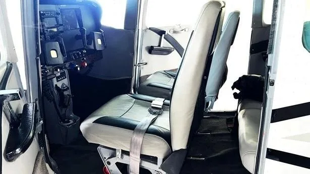 The front two seats of the aircraft cabin, with a partial view of the cockpit instrument panel.