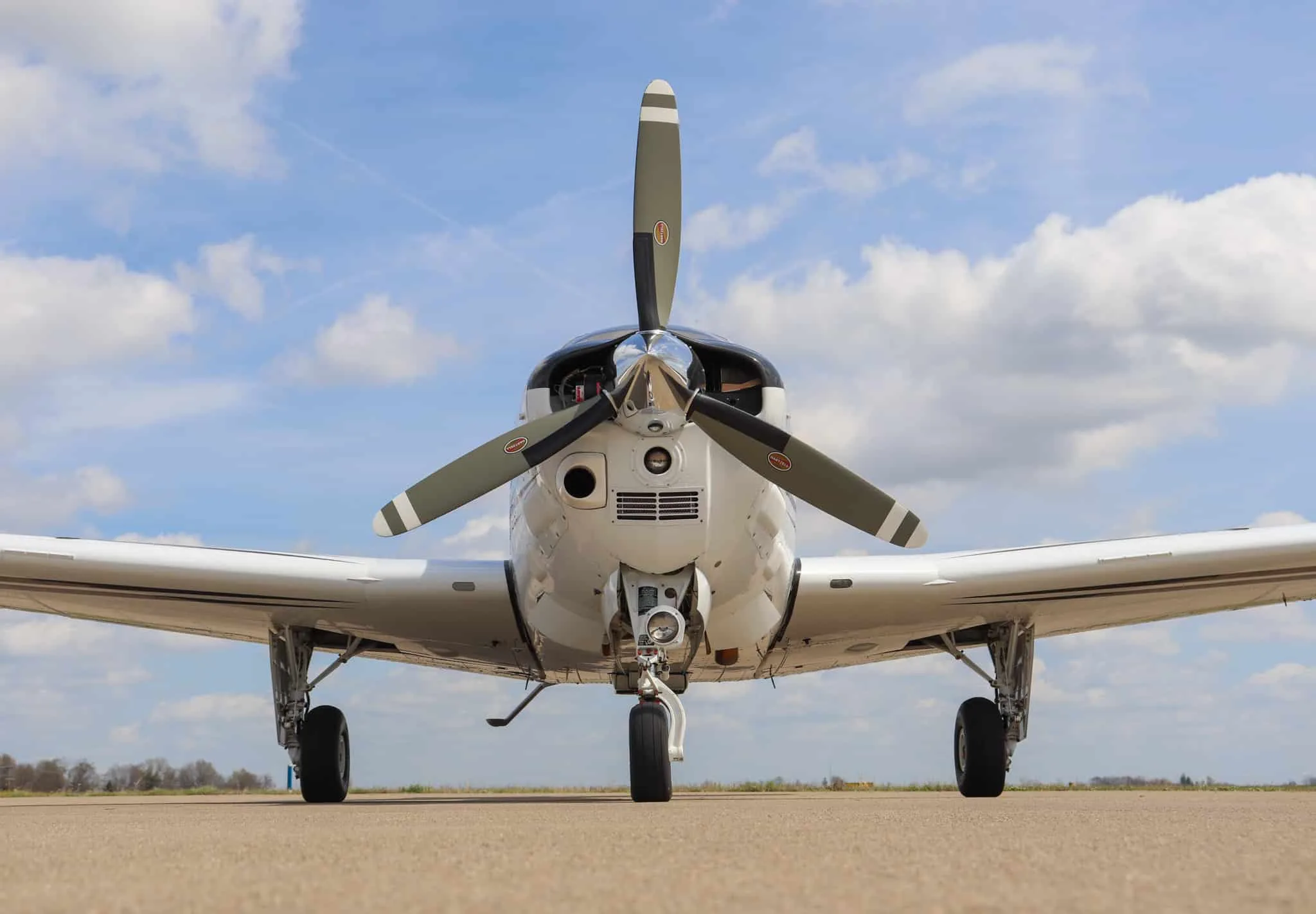 A low-angle, close-up front view of the propeller and nose of a white Beechcraft Bonanza G36 aircraft.