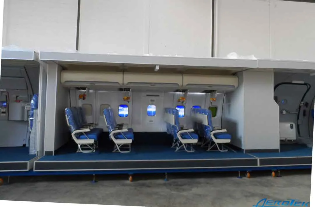 A training mock-up of an aircraft cabin with blue seats and illuminated windows.