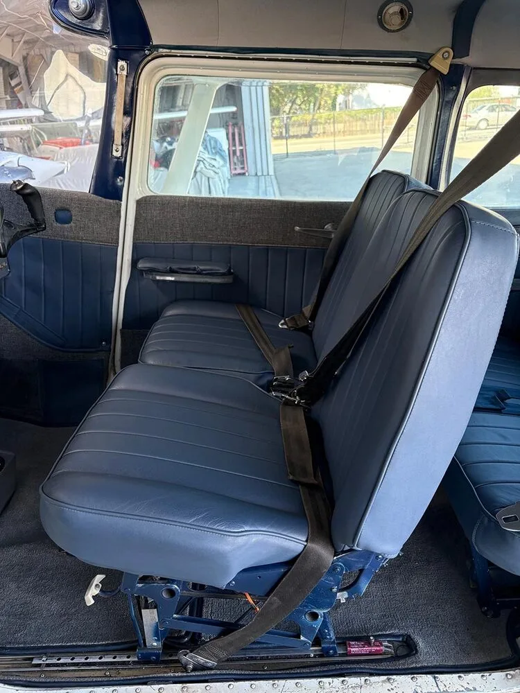 The blue upholstered passenger seats with seatbelts inside a small aircraft cabin, viewed from the rear.