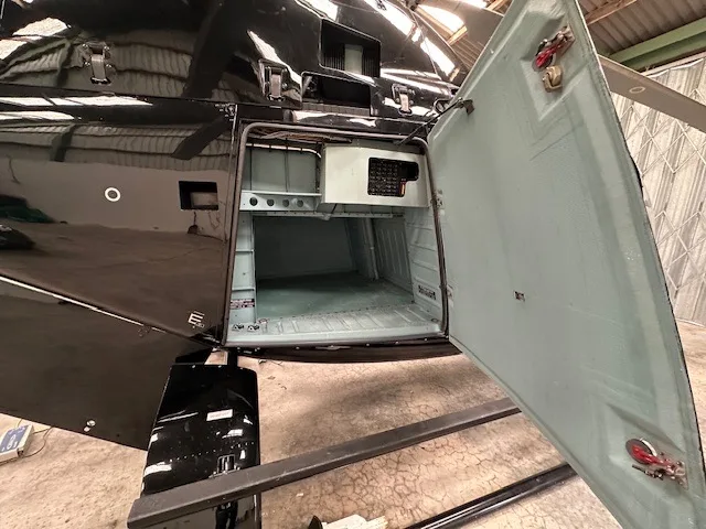 Rear storage compartment of the black helicopter with the door open.