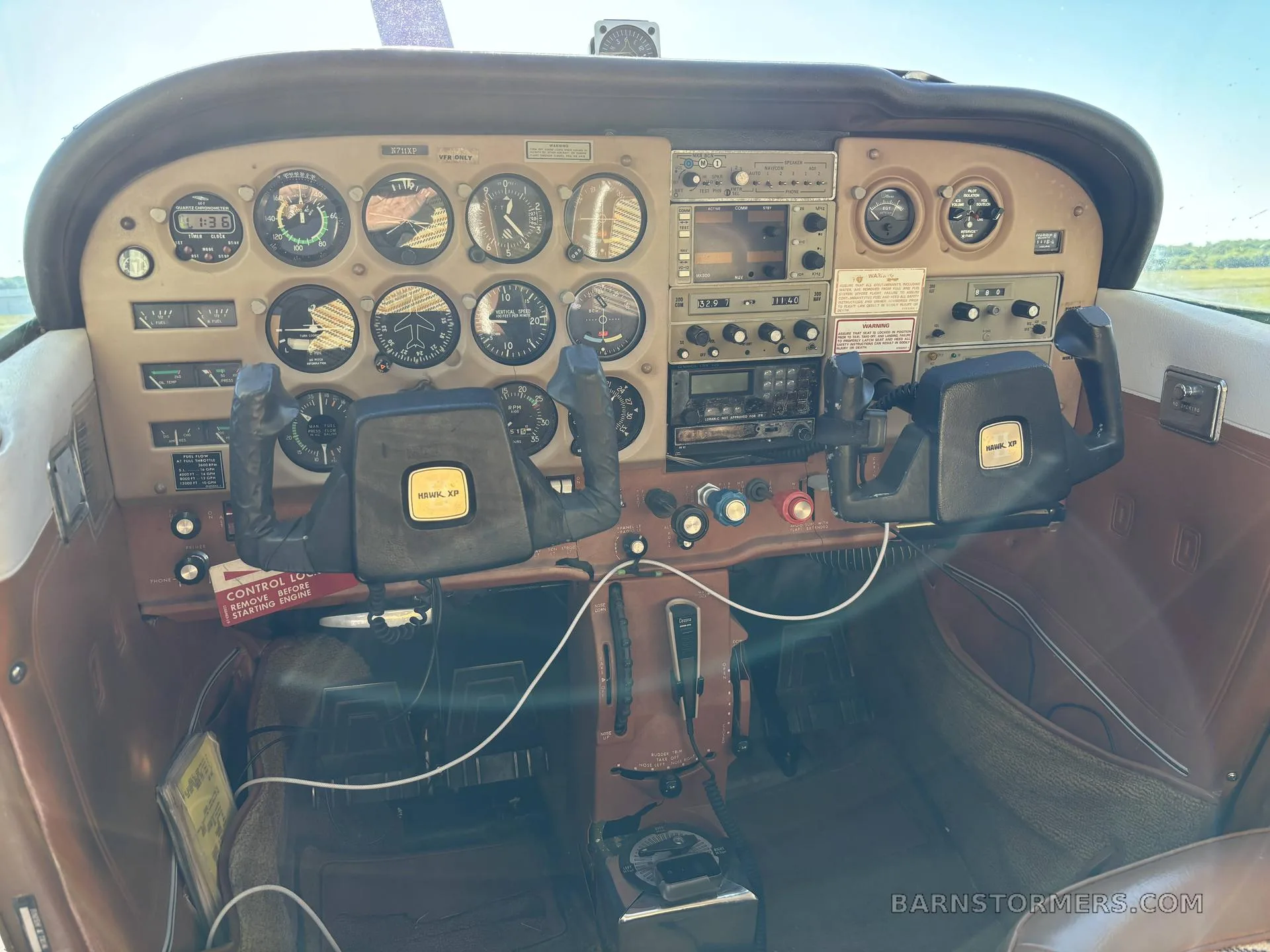 The cockpit of a Cessna 172, featuring a brown instrument panel with analog gauges and two control yokes.