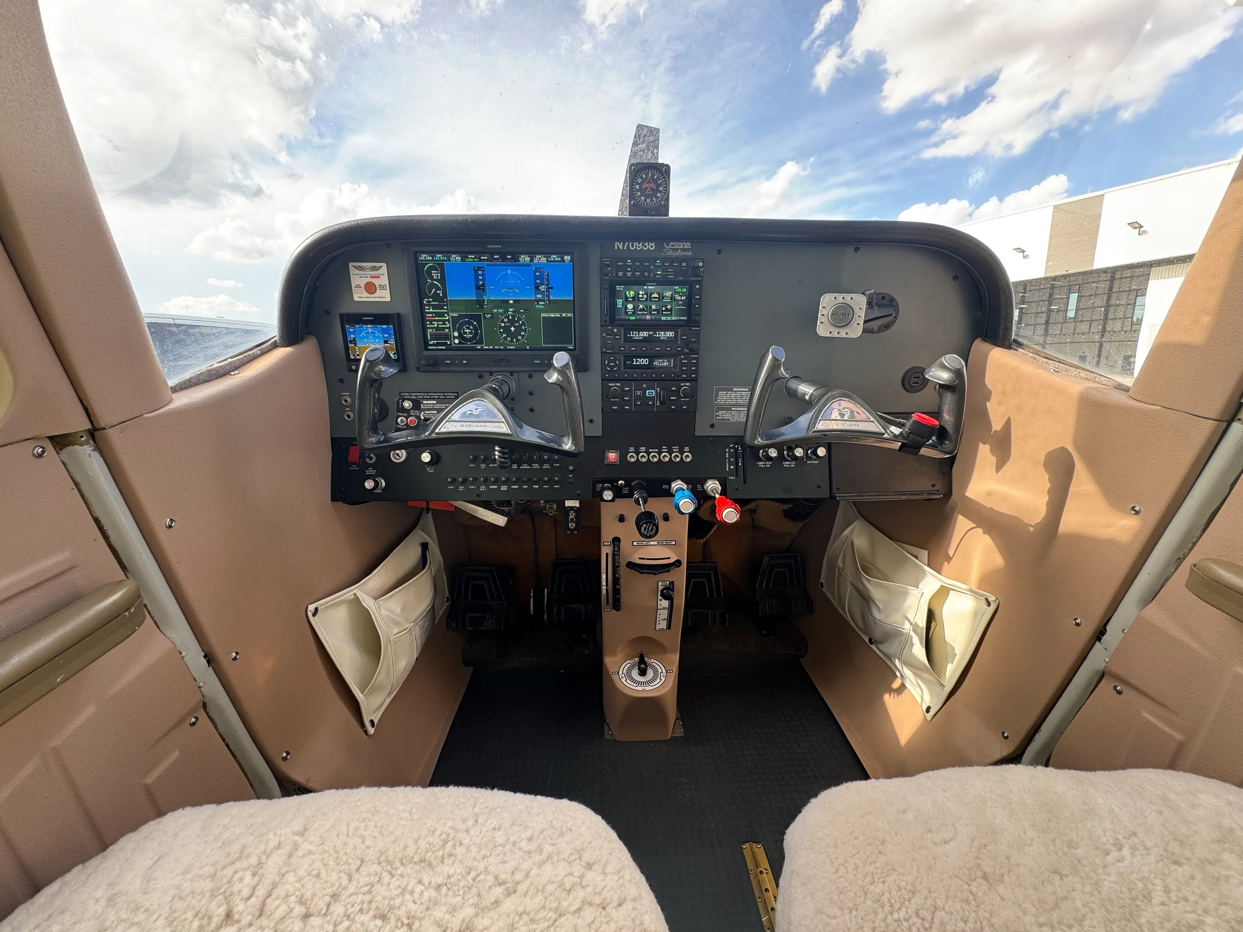 The cockpit of a Cessna aircraft with modern Garmin avionics and sheepskin seat covers.