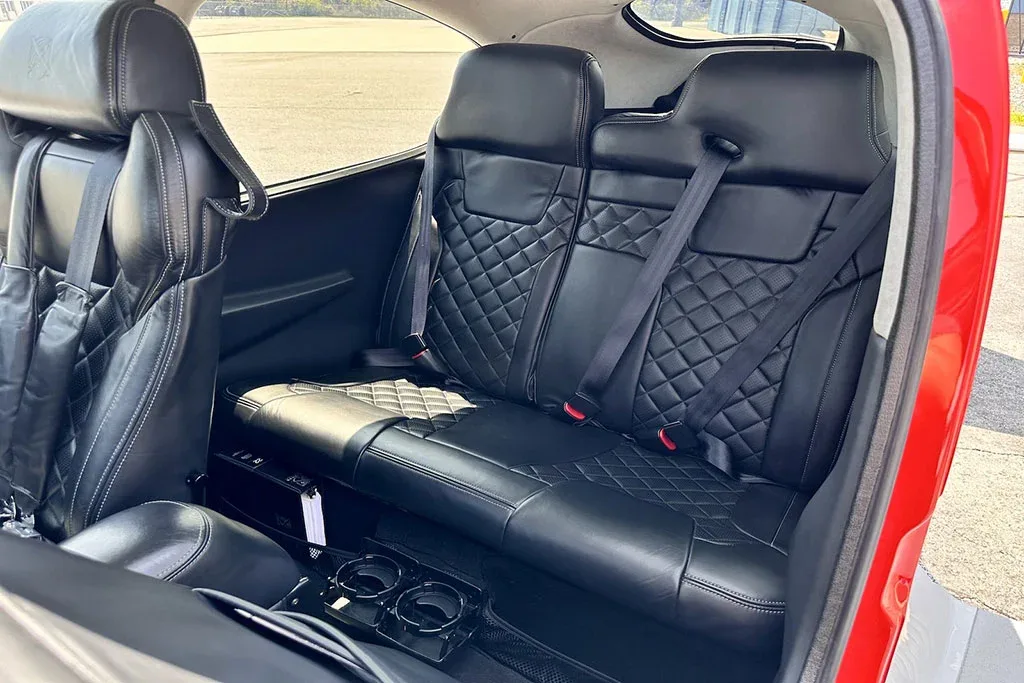 The rear black leather seats of a Cirrus SR22 aircraft, featuring a diamond-stitched pattern.