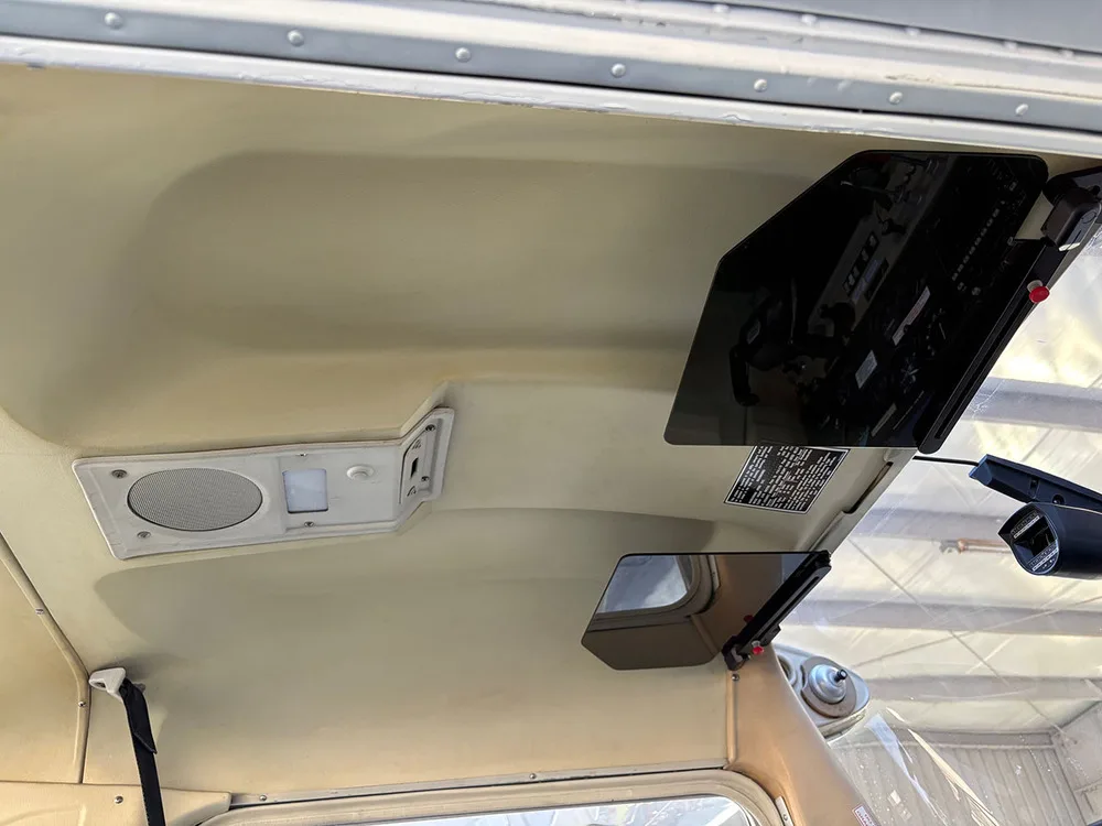The beige ceiling and sun visors of an aircraft interior, with a speaker and light panel visible.