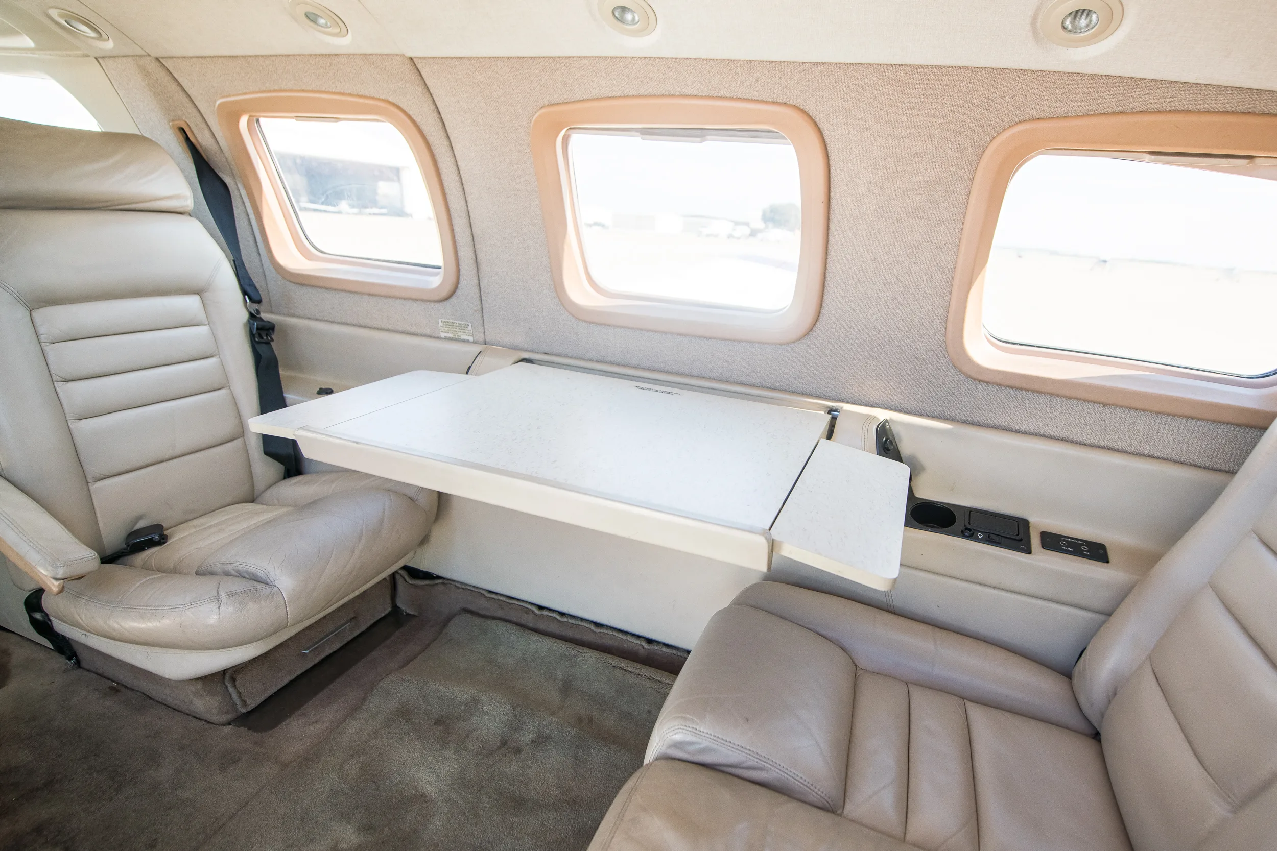 Another view of the N529WM aircraft's beige interior, showing two facing seats with a large fold-out table between them.