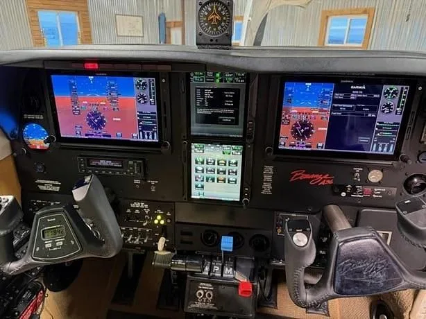 The cockpit of a Beechcraft Baron 58, featuring modern Garmin glass panel displays and traditional controls.