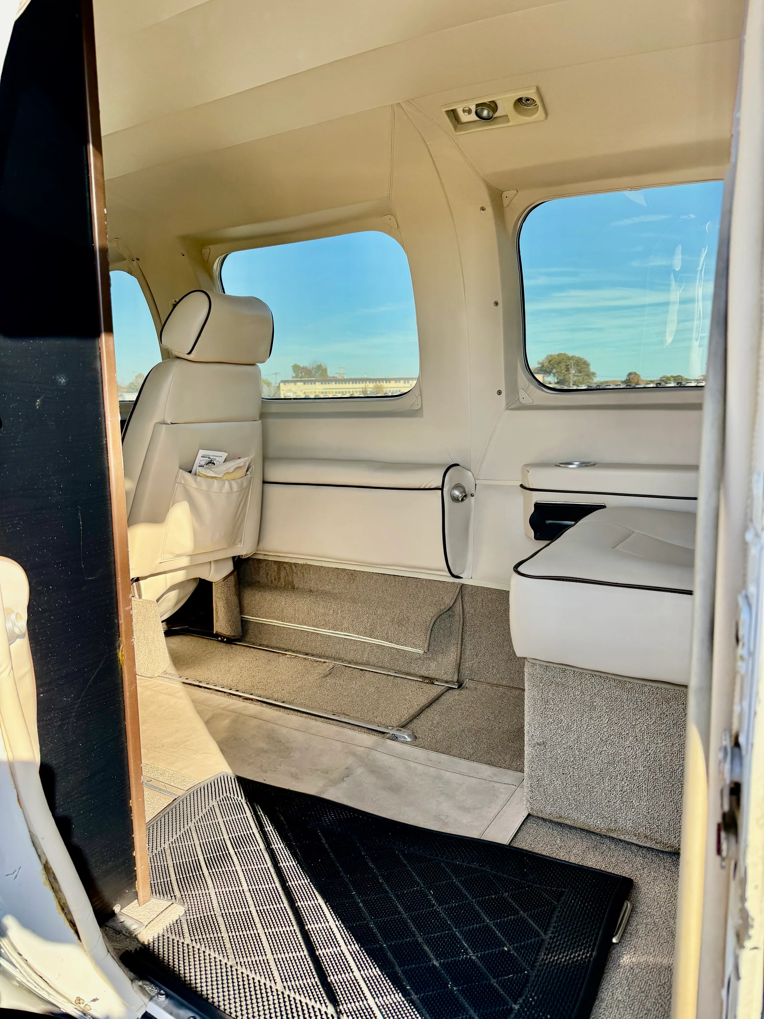 A view into the aircraft's cabin from the open entry door, showing cream-colored seats and windows.
