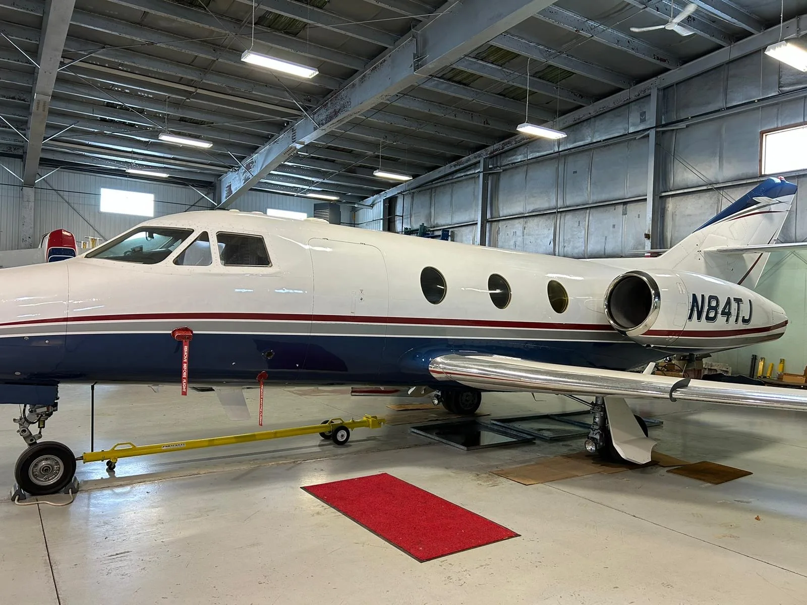 Side view of the aircraft N84TJ in a hangar.