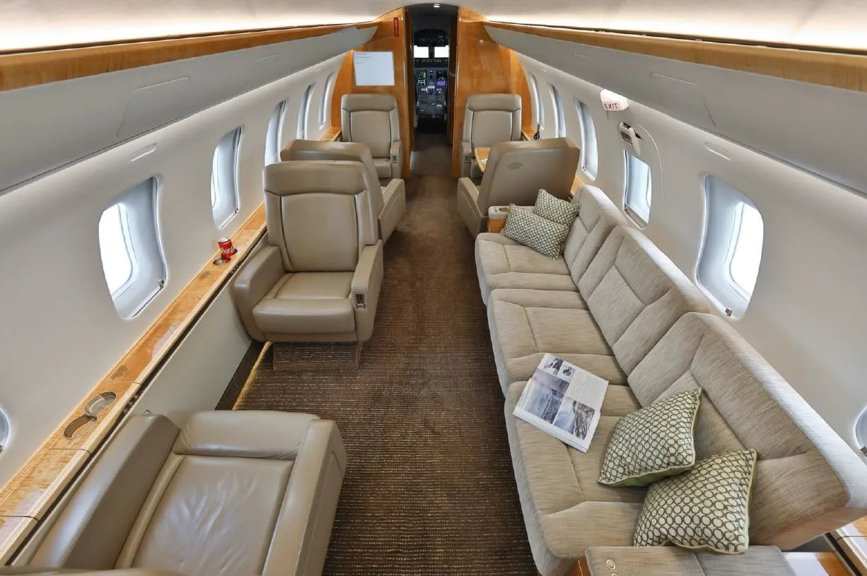 The luxurious interior cabin of a private jet features beige leather seats and a comfortable sofa.