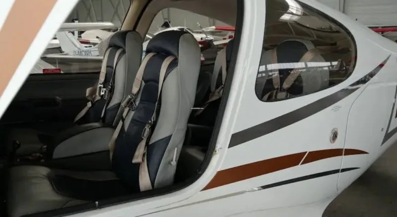 The interior cabin of a Cirrus SR22 showing gray and dark blue seats with seatbelts.