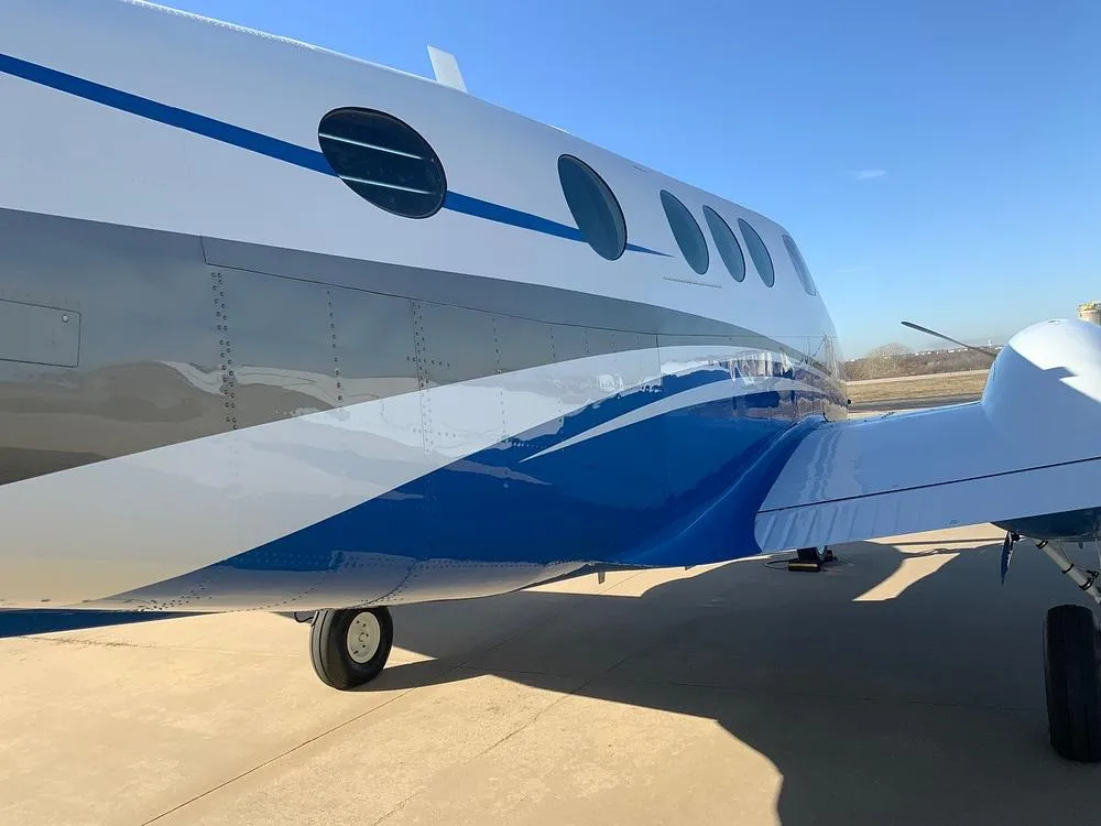 A close-up side view of the white and blue paint scheme on the fuselage of the turboprop aircraft.
