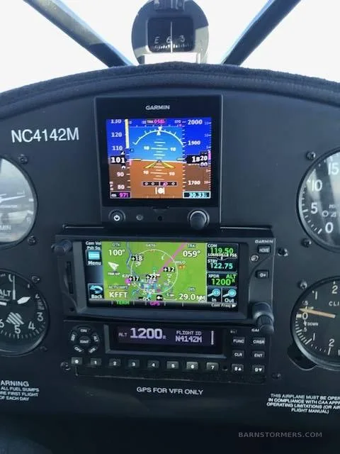 The cockpit instrument panel of an aircraft, featuring Garmin GPS displays and analog gauges.