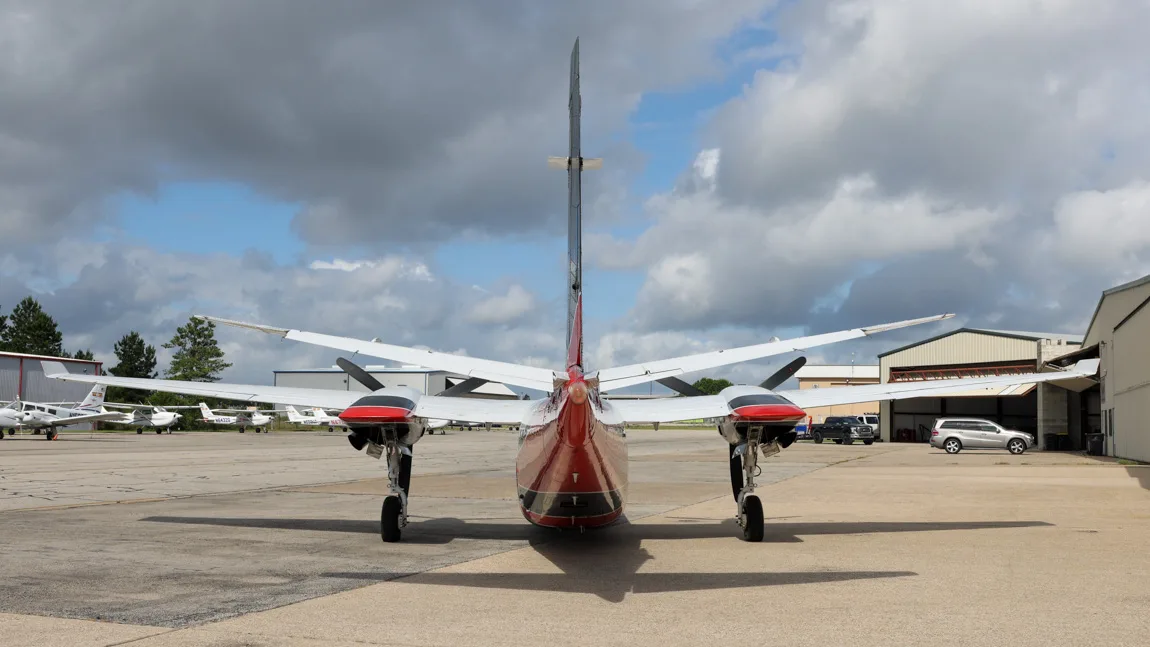 Rear view of a white, black, and red twin-engine aircraft, N84GU, parked on an tarmac.