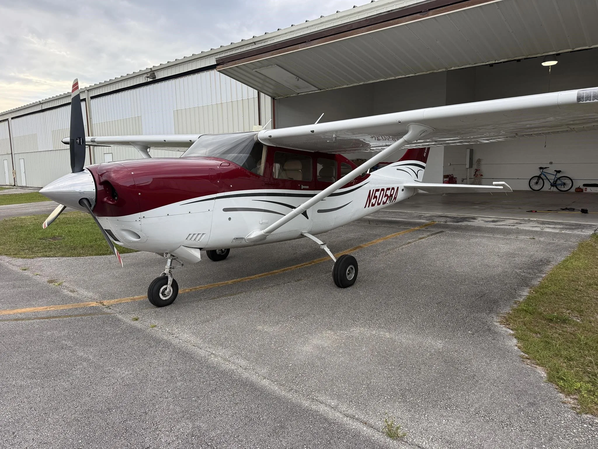 A red and white Cessna Stationair TC aircraft (N505RA) parked outside a hangar, viewed from the front left.