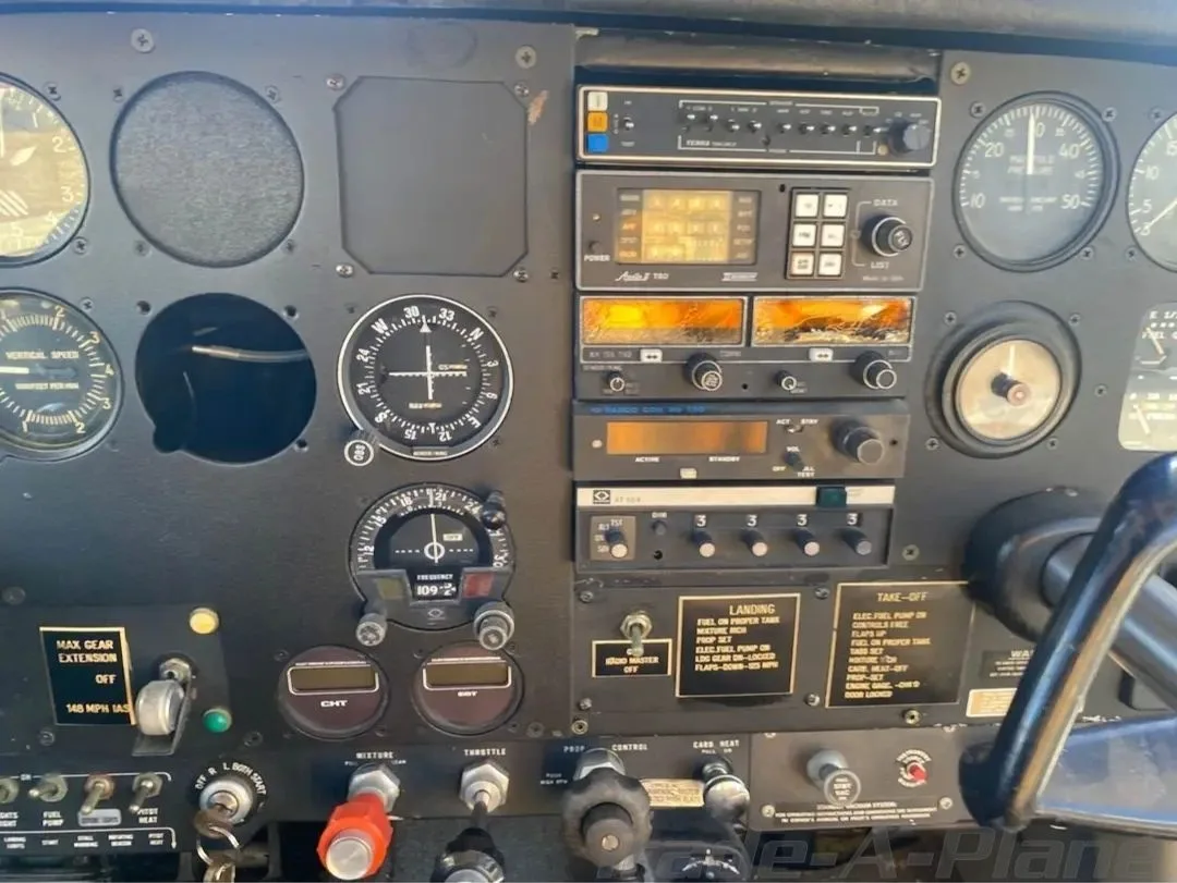 A close-up view of an aircraft's black instrument panel with various gauges, radios, and controls.