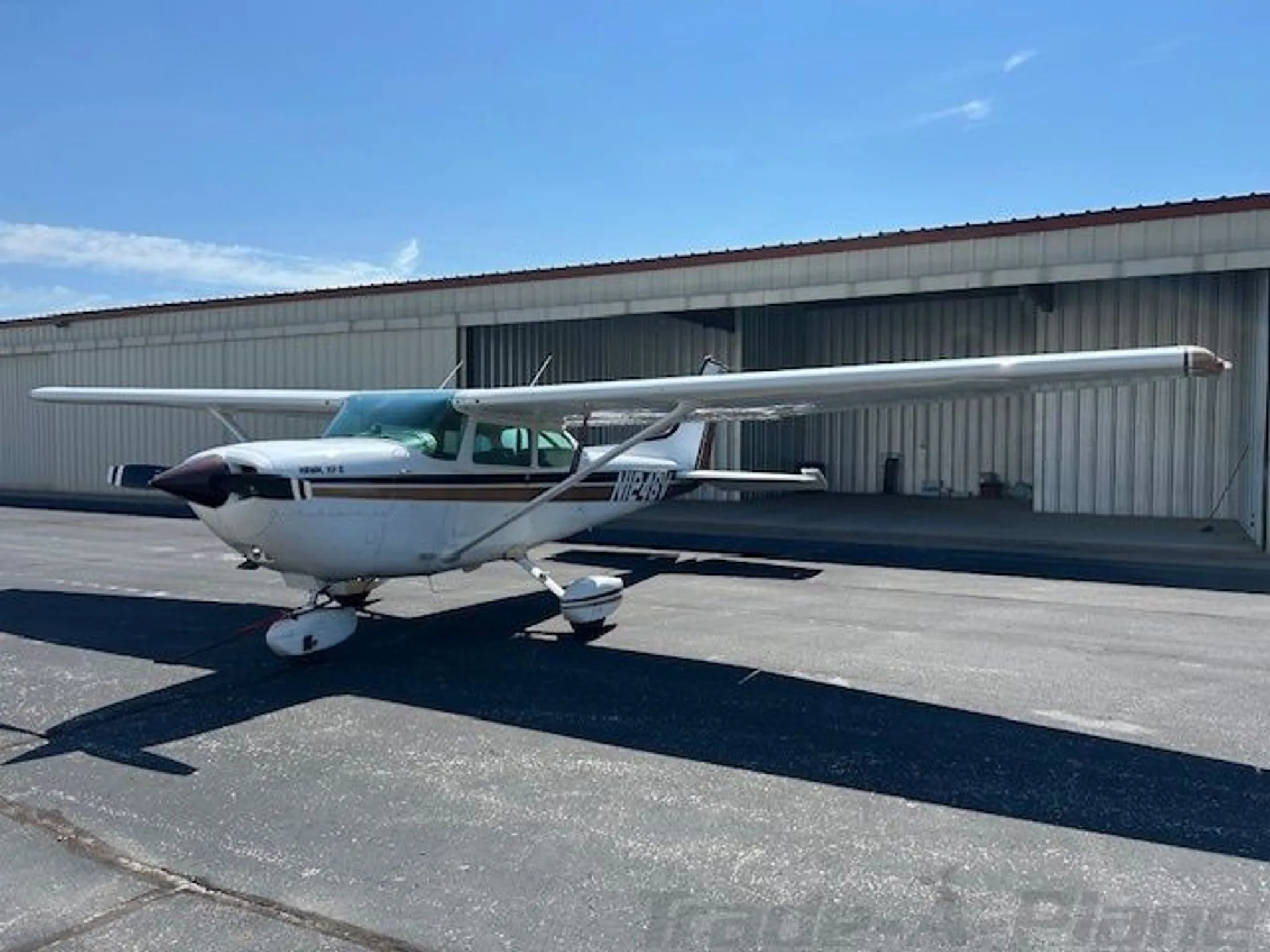 Three-quarter front view of a white and brown Cessna R172K (N1246V) on an asphalt ramp.
