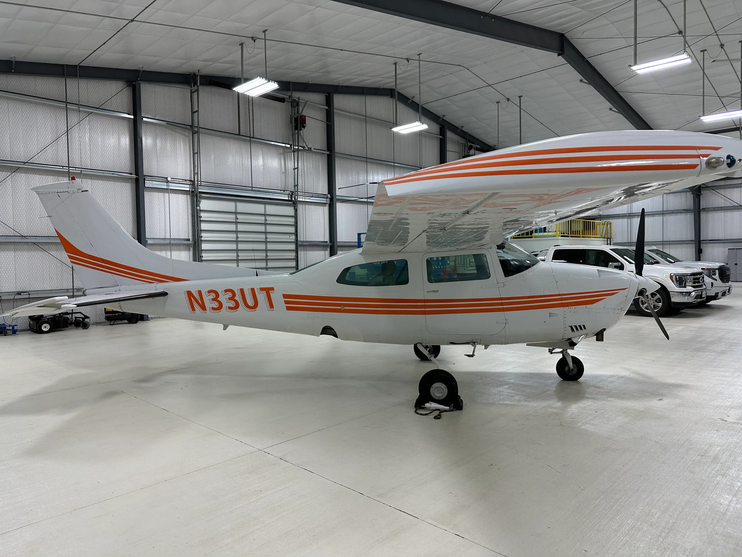 A Cessna 206 Stationair aircraft with orange stripes parked in a hangar.
