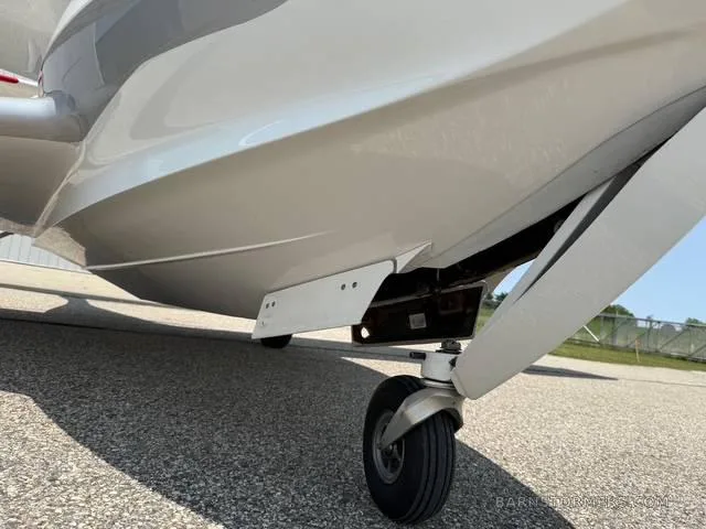 A close-up view of the front landing gear and the underside hull of a white and silver ICON A5 aircraft.