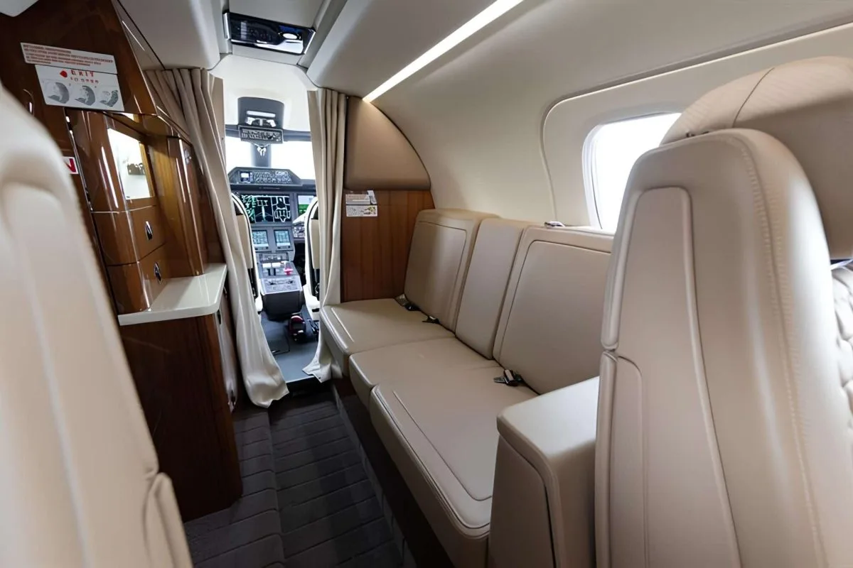 A view of the aircraft cabin with seats and a view of the cockpit.