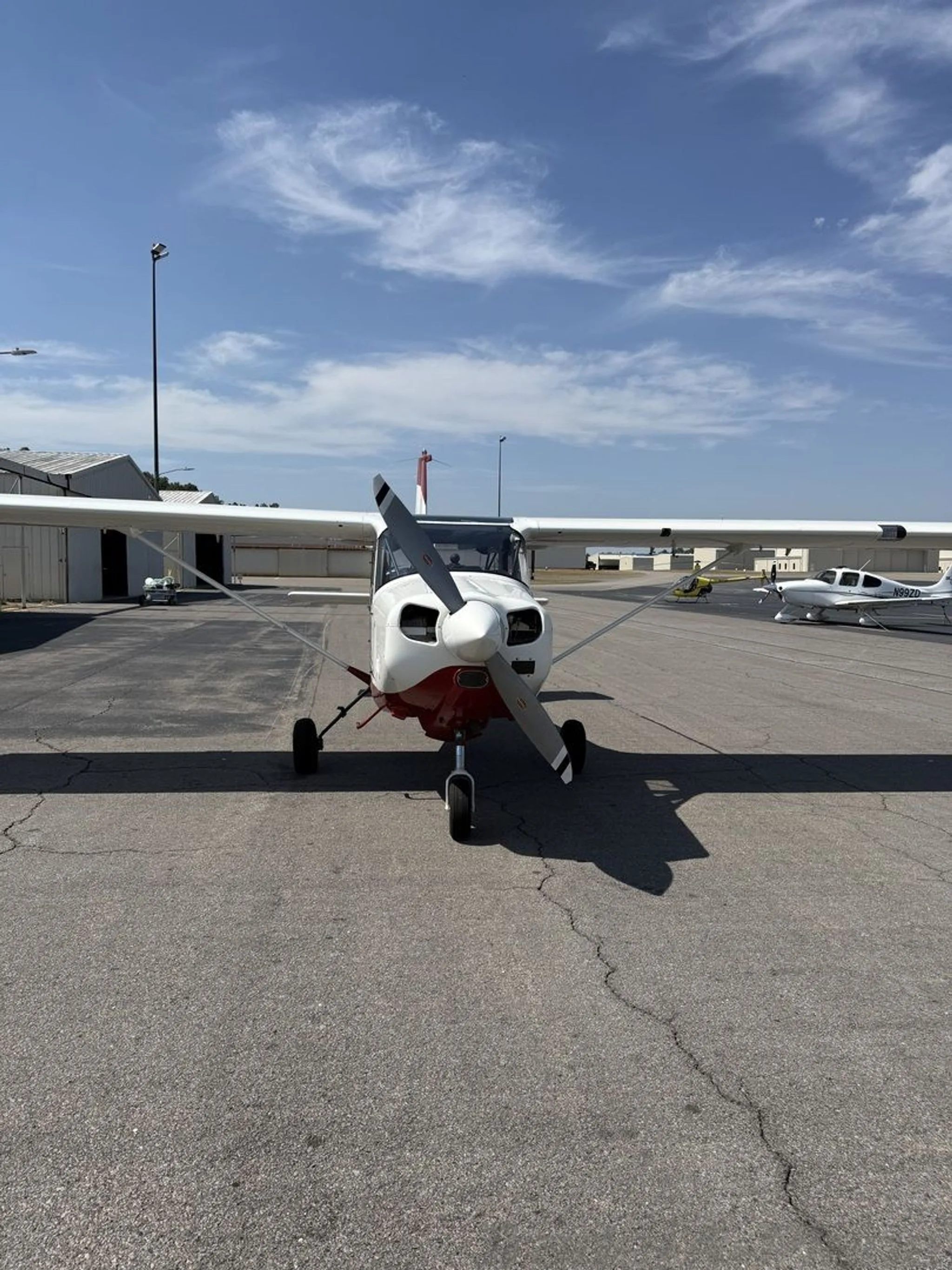 Front view of the white and red single-engine aircraft N733AX on an airfield.
