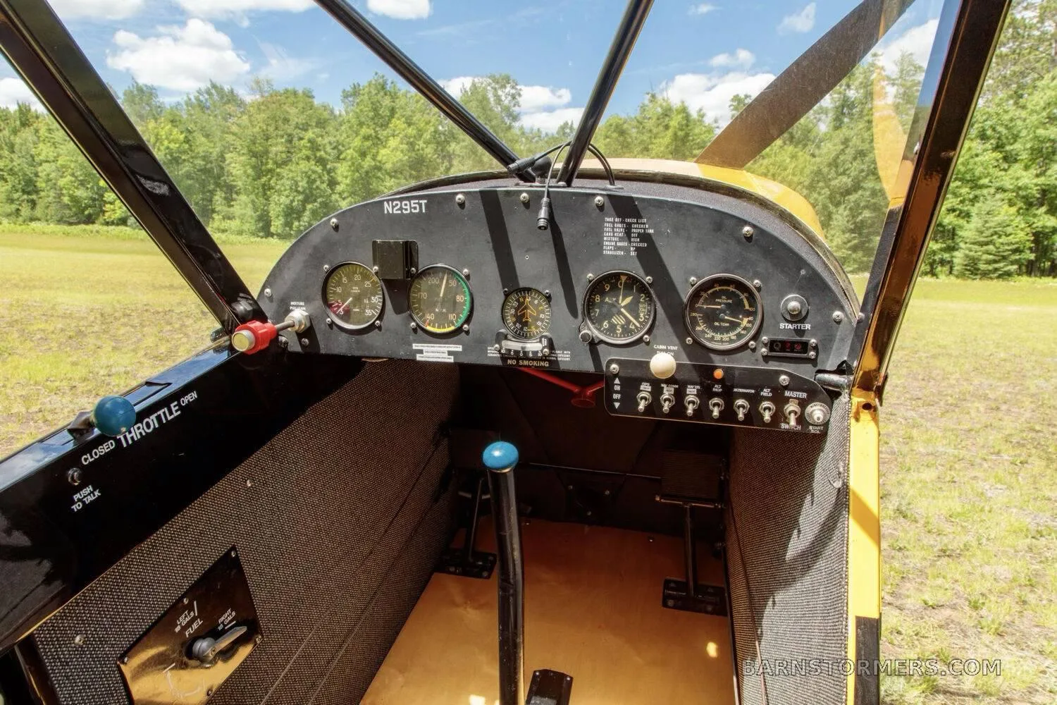 The cockpit of a yellow aircraft, showing the instrument panel with gauges, controls, and the N295T registration.