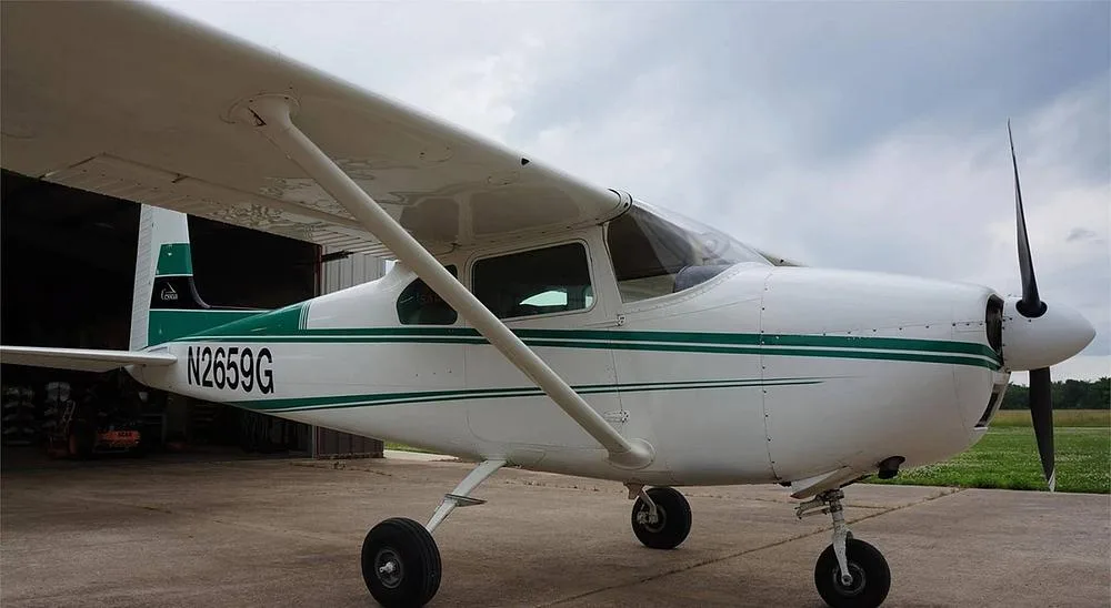 A white single-engine propeller aircraft with green stripes and registration N2659G, parked on a concrete pad.