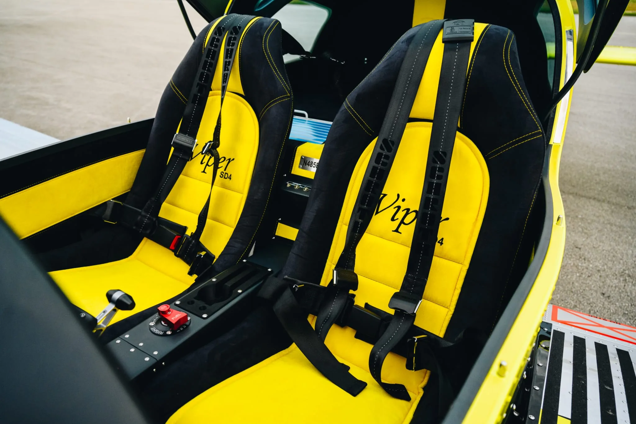 The yellow and black two-seat interior of a Viper SD4 aircraft, showing the registration N485EA on a panel.