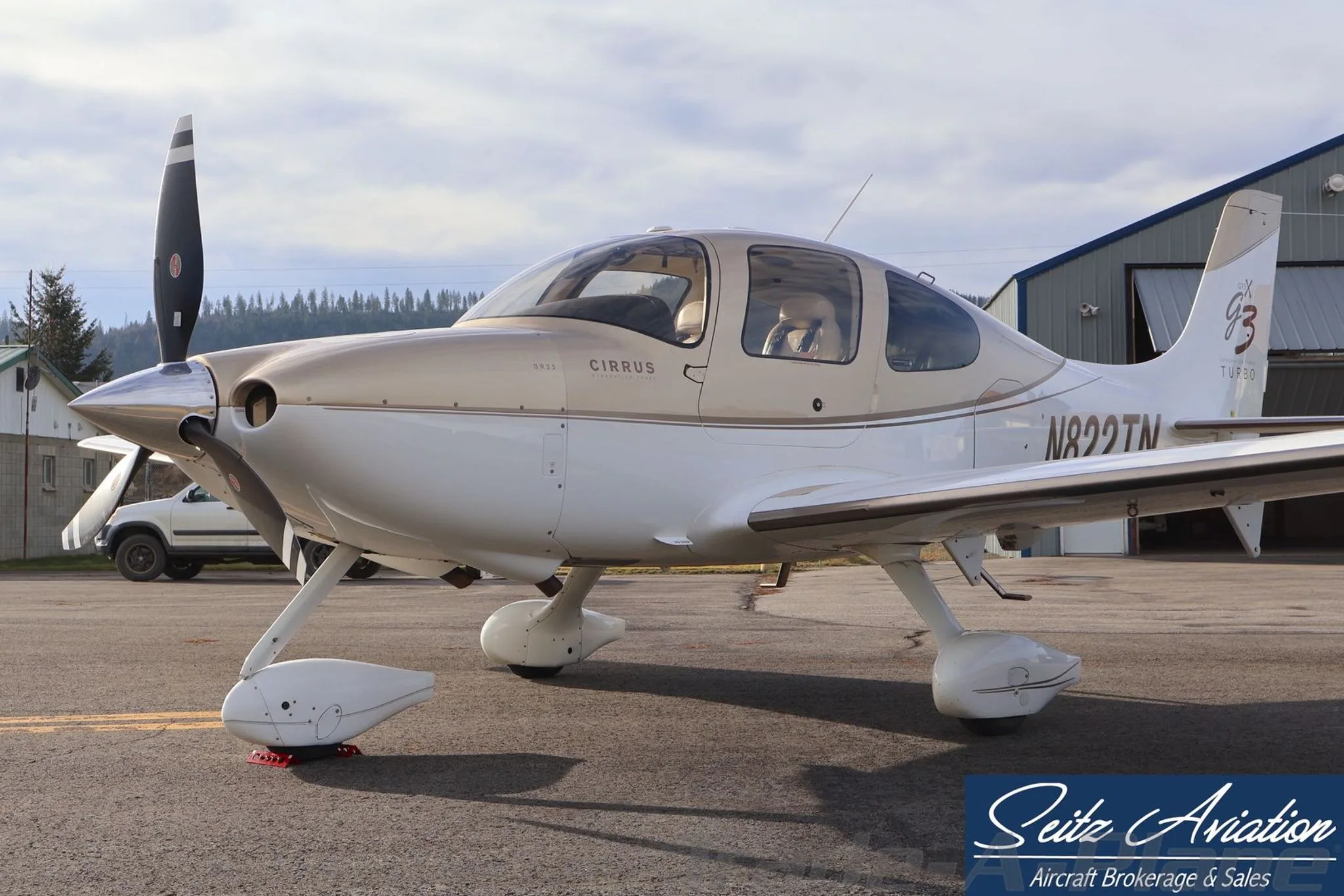 Front-side close-up view of the Cirrus SR22T aircraft N822TN, showing the cockpit and propeller, parked near a hangar.