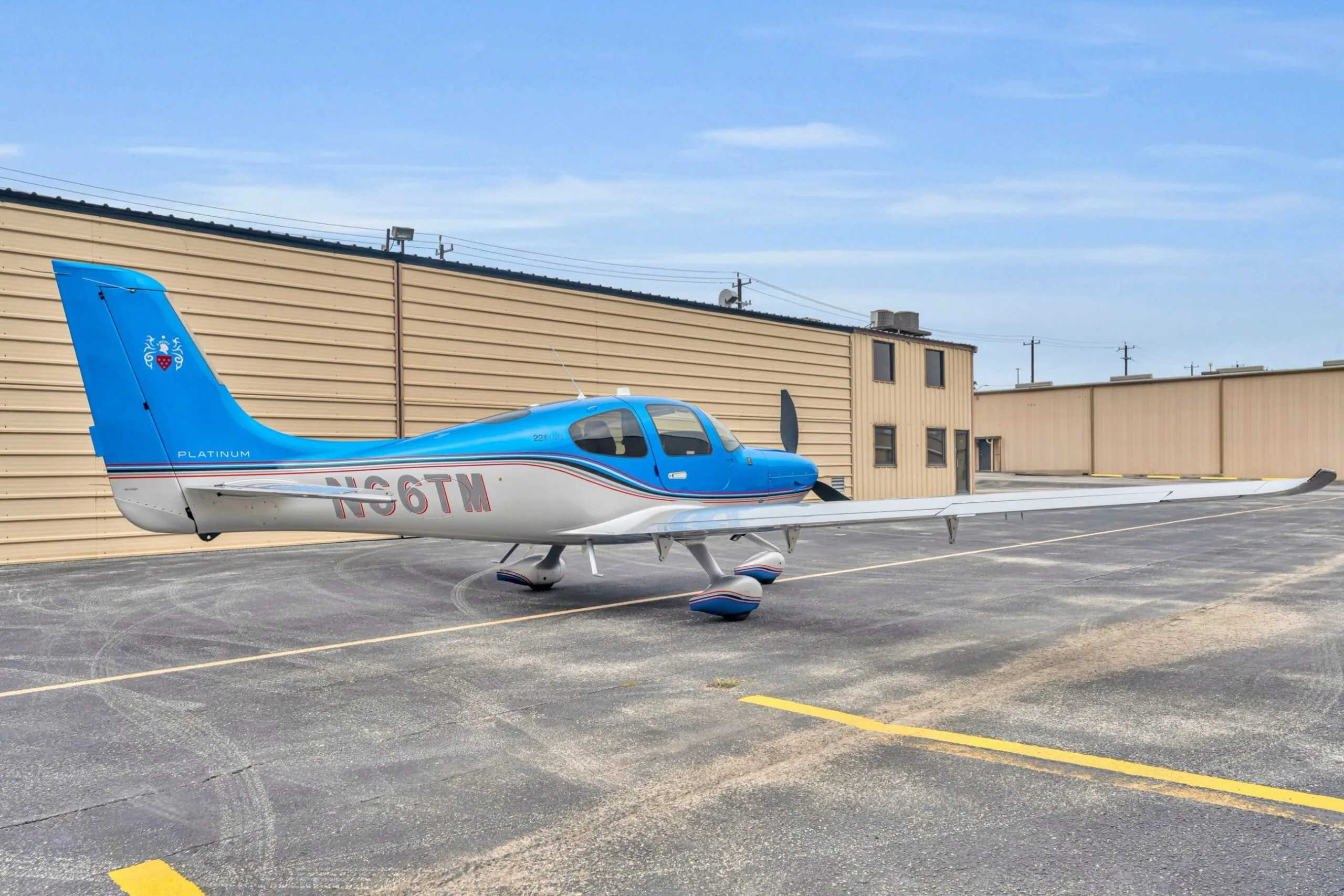 A three-quarter rear view of the blue and silver Cirrus SR22T GTS aircraft N66TM, parked on an asphalt ramp.