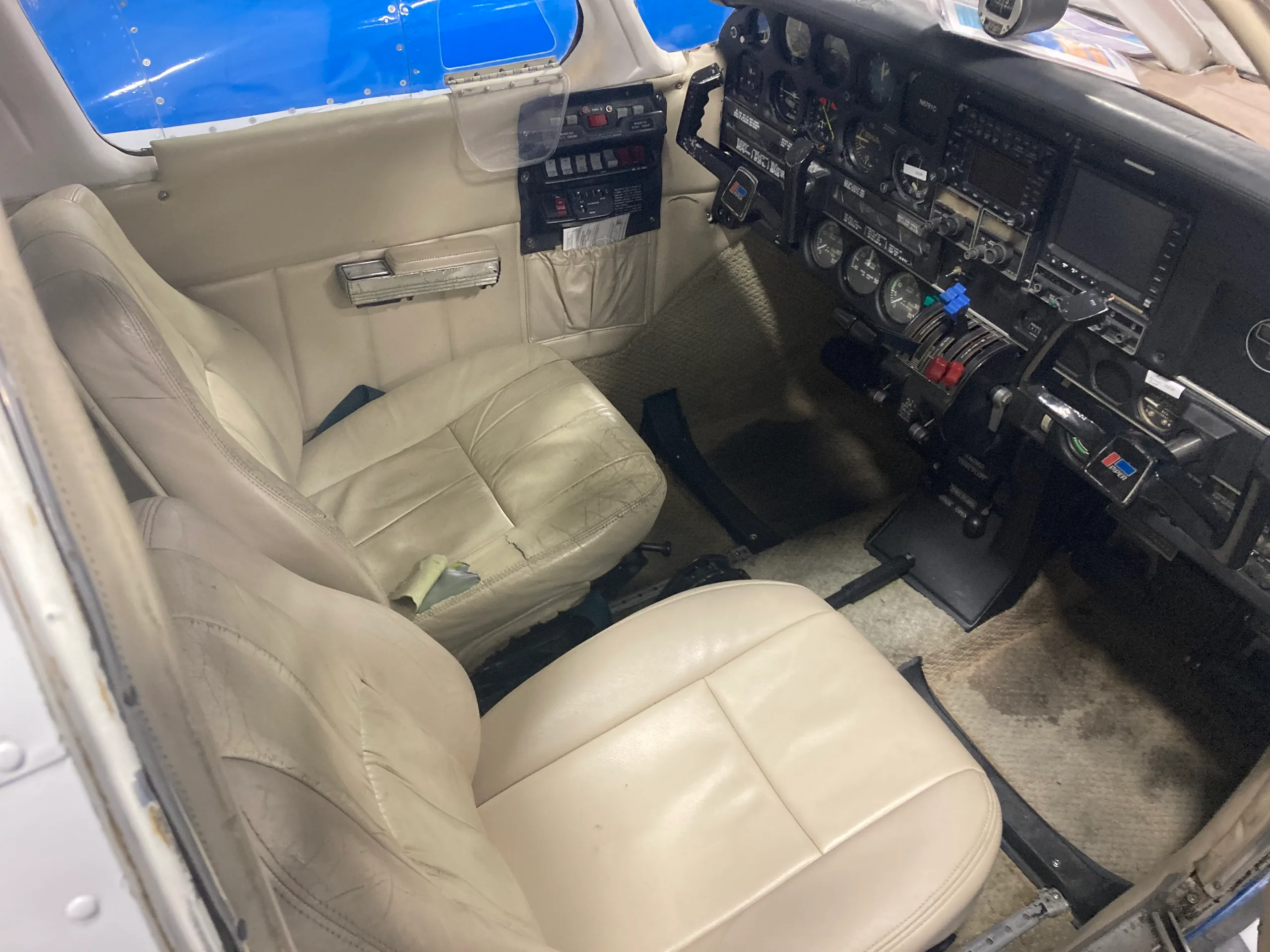 The beige leather front seats and part of the cockpit of a Piper Seneca.