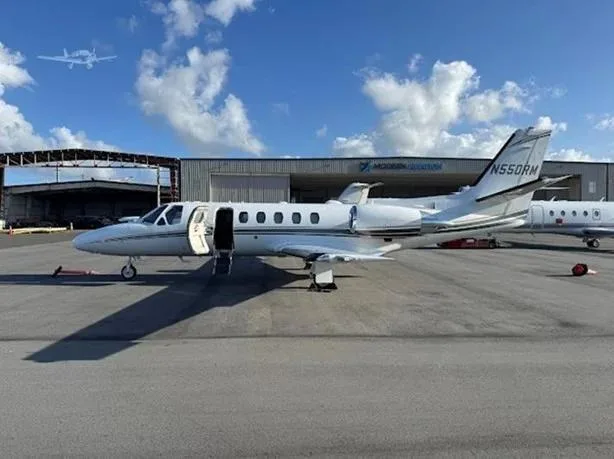 A white Cessna Citation business jet with tail number N550RM is parked on a tarmac with its main door open.